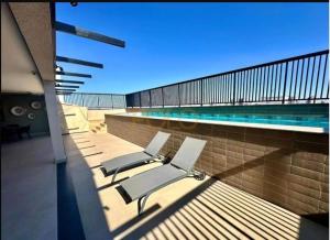 a swimming pool with two lounge chairs next to a pool at Studio moderno, rooftop com piscina, próx UFU in Uberlândia