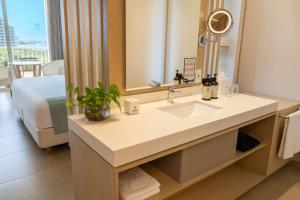 a bathroom with a sink and a mirror and a bed at Hotel Irotama Lago in Santa Marta