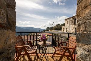 a balcony with chairs and a table with flowers on it at Manoli's Light Stone House in Vathi