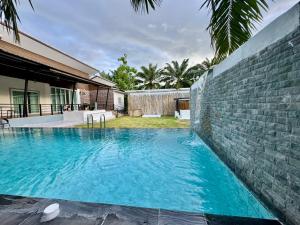 a swimming pool in front of a brick wall at บ้าน อินอักษร in Pumriang