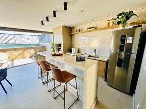 a kitchen with a stainless steel refrigerator and a counter at Studio moderno, rooftop com piscina, próx UFU in Uberlândia