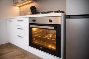 a kitchen with an oven with its door open at Le Suite del Pastore, Monolocale con Terrazza Privata e Parcheggio Facile, vicino al Centro in Lecce +16 photos