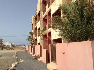 a pink building with a fence next to a beach at Apto Martins - Residencial Inês N 23 in Vila do Porto