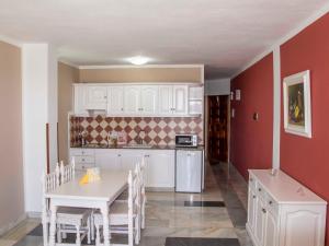a kitchen with white cabinets and a table and chairs at Apartamentos Tapahuga in Playa de Santiago