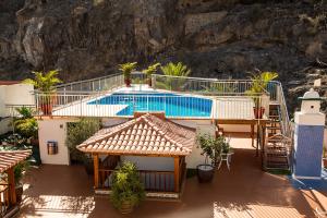 a house with a swimming pool in front of a mountain at Apartamentos Tapahuga in Playa de Santiago