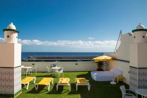 a balcony with chairs and a bed and a table at Apartamentos Tapahuga in Playa de Santiago