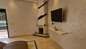 a living room with a fireplace and a tv on a wall at Prestige Villa in Marrakesh