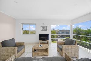 ein Wohnzimmer mit zwei Sofas und einem Fernseher in der Unterkunft Beachfront Family Apt - Ocean Views in Diamond Beach