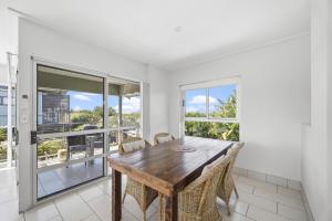 ein Esszimmer mit einem Holztisch und Fenstern in der Unterkunft Beachfront Family Apt - Ocean Views in Diamond Beach