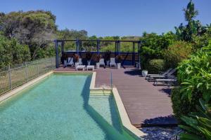 ein Swimmingpool mit Stühlen und einer Holzterrasse in der Unterkunft Beachfront Family Apt - Ocean Views in Diamond Beach