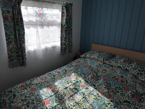 a bedroom with a bed with a quilt and a window at "Trinity" Chalet in Sundowner Hemsby in Hemsby