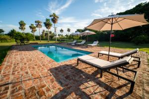 a swimming pool with an umbrella and lounge chairs and an umbrella at Estancia Iberá in Colonia Carlos Pellegrini