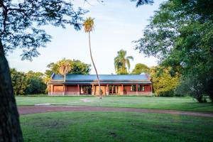 a red building with a palm tree in front of it at Estancia Iberá in Colonia Carlos Pellegrini