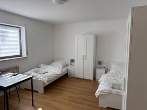 a white room with two beds and a table at Ferienwohnung LuMa in Rottenacker in Rottenacker