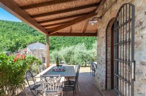 a patio with a table and chairs under a wooden roof at Villa Badia, large villa in Umbria with private pool in Città di Castello