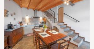 a kitchen and dining room with a table and a staircase at La casa dei Pasqui' in Bollone