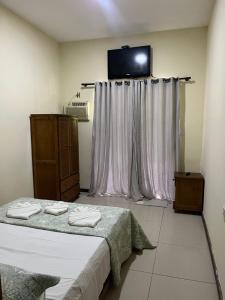 a bedroom with a bed and a tv on the wall at Suíte dos Reis in Angra dos Reis