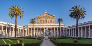 a building with a statue and palm trees in front at Savi Guest House metro B S Paolo in Rome +74 photos
