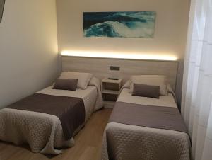 a room with two beds in a room with a painting at Pensión Plaza in Quintáns +45 photos