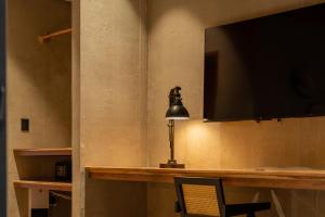 a desk with a lamp and a television on a wall at The Quiet Garden in Jacó