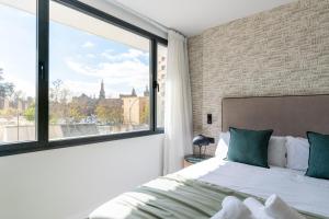 a bedroom with a bed and a large window at Apartamentos Plaza España - Enjoy Sevilla in Seville