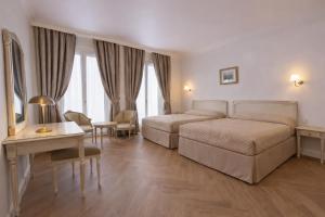 a hotel room with two beds and a desk at Grand Hôtel Moderne in Lourdes