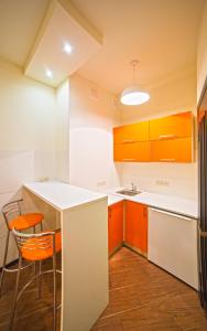 リヴィウにあるApartment on Rappoporta 7b - 2のキッチン(オレンジと白のキャビネット、テーブル、椅子付)