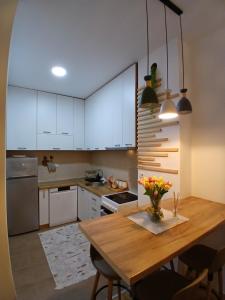 a kitchen with white cabinets and a wooden table at Jednosoban stan Tivat in Tivat