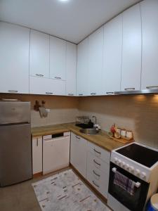 a kitchen with white cabinets and a sink at Jednosoban stan Tivat in Tivat +5 photos