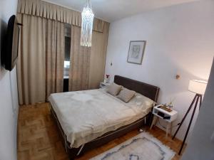 a small bedroom with a bed and a chandelier at Jednosoban stan Tivat in Tivat