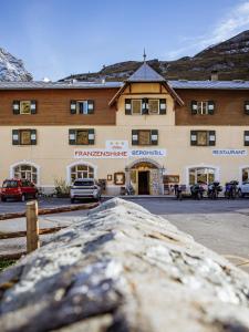 a large building with cars parked in front of it at Berghotel Franzenshöhe in Trafoi