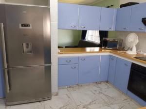 a kitchen with a stainless steel refrigerator and white cabinets at Turtle Sands Holiday Home in Richards Bay