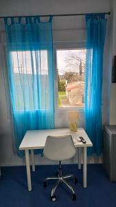 a desk and a chair in a room with a window at White and Blue in Mesimvría