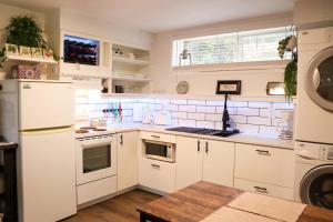 a kitchen with white cabinets and white appliances at The Kalamoir Suite in West Kelowna