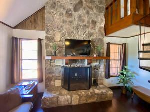 a living room with a stone fireplace with a tv at Rusty Rio in Concan