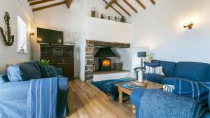 a living room with blue couches and a fireplace at Pen Bonc in Moelfre