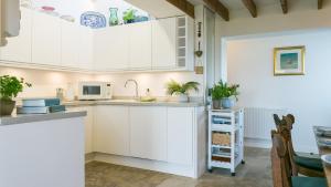 a kitchen with white cabinets and a sink at Pen Bonc in Moelfre