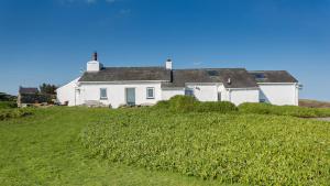 a white house on top of a grassy hill at Pen Bonc in Moelfre