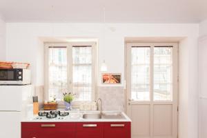 a kitchen with red cabinets and two windows at Appartamento Porta Susa in Turin