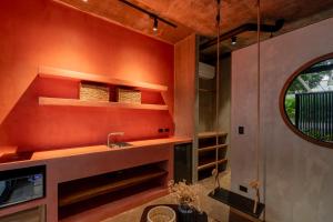 a kitchen with orange walls and a sink and shelves at The Surfer's Base in Jacó