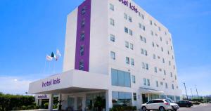 a hotel building with a car parked in front of it at Hotel Lois Express Monterrey Aeropuerto La Fe in Monterrey