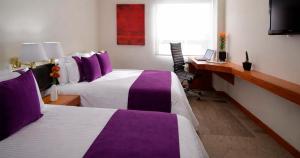 a hotel room with two beds and a desk at Hotel Lois Express Monterrey Aeropuerto La Fe in Monterrey