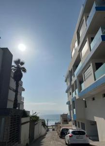 a building with a palm tree next to the ocean at La corniche in Kenitra