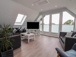 a living room with couches and a flat screen tv at Mikes Place On The Cove in Rhyl