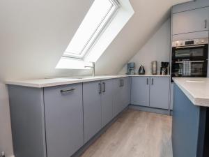a kitchen with white cabinets and a skylight at Mikes Place On The Cove in Rhyl