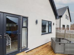 a white house with black windows and a wooden deck at Mikes Place On The Cove in Rhyl