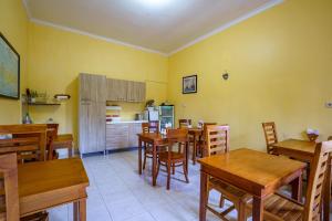 a dining room with wooden tables and a kitchen at Whiterose Guesthouse in Senggigi