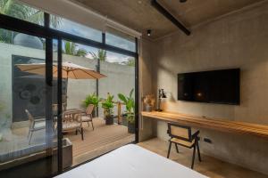a room with a television and a patio with a table at The Digital Nomad Den in Jacó