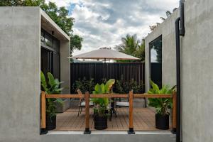 a patio with a table and umbrella and plants at The Digital Nomad Den in Jacó