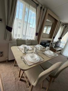 a dining room table with chairs and plates on it at 6 berth caravan in Ingoldmells opposite beach in Ingoldmells
